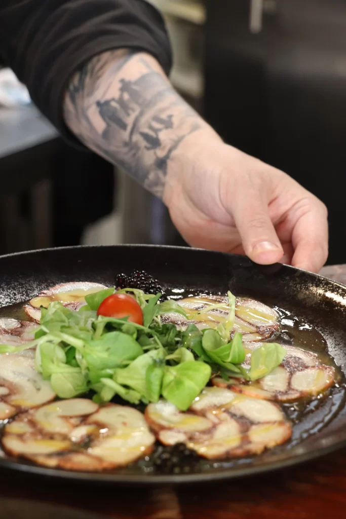 Octopus carpaccio with olive oil, lamb’s lettuce, and cherry tomato being served at Konoba Malo Misto restaurant in Zadar