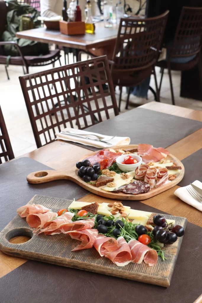 Two traditional Croatian charcuterie boards with prosciutto, cheese, olives, grapes, and nuts served at a rustic table inside Konoba Malo Misto in Zadar