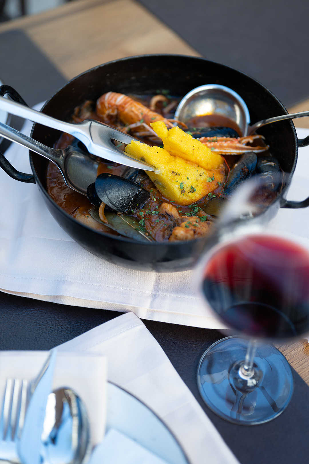 Seafood dish served in a pot with wine at the table